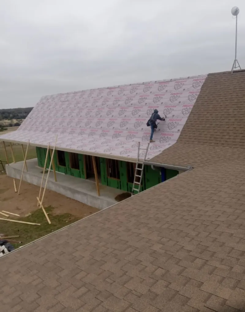 Worker preparing underlayment for a metal roof installation in St. Francis